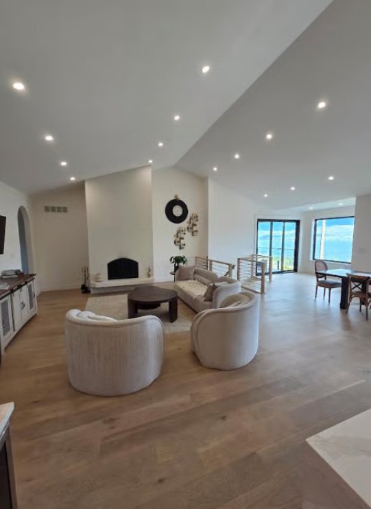 Open living room with crisp white walls, fireplace and vaulted ceiling